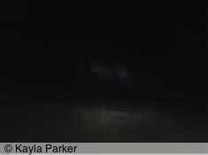 kayla's photo of full moon, visible as light bands in sky of black clouds