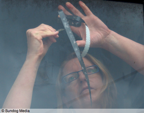 Stuart's photo of Kayla drawing on a strip of 16mm balck film with a scalpel, using the window as a window/lightbox
