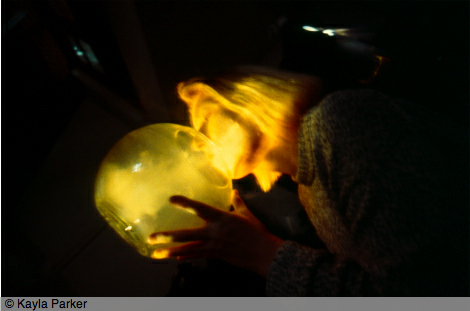 35mm colour transparency depicts Kayla Parker blowing into a glass orb, lit from below - the breath is visible