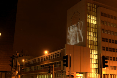Photo taken during the evening from North Hill, showing projection of the film Hold onto the south-facing wall of the Davy Building at University of Plymouth