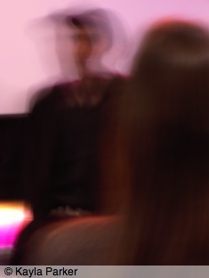 Kayla's photo of Jem Cohen sitting on the stage at Aurora in Norwich; hand-held camera, no flash