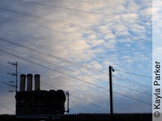 Kayla's photo of pale crescent moon in curdled clouds over May Terrace rooftop