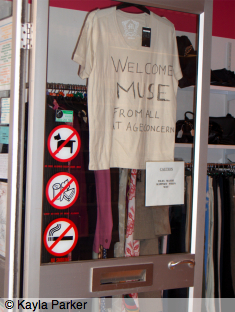 Photo of T-shirt on hanger in open door of the Teignmouth Age Concern shop; hand-writen message on the T-shirt reads: 
