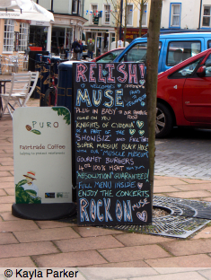 Photo of blackboard sign leaning against tree outside Teignmouth café; sign written in coloured chalk: 