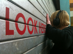 photo of Kayla looking at a cage of budgies, close to the Peep Show at Project Space 11